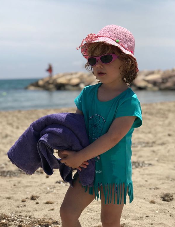 Nena a la platja amb ulleres de sol